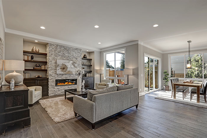 Contemporary living room with stone fireplace, hardwood flooring, and open dining area